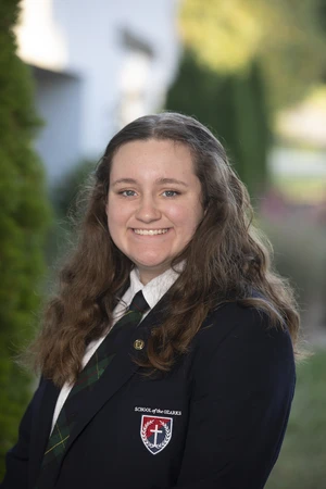 Girl with brown hair smiling, wearing school uniform.