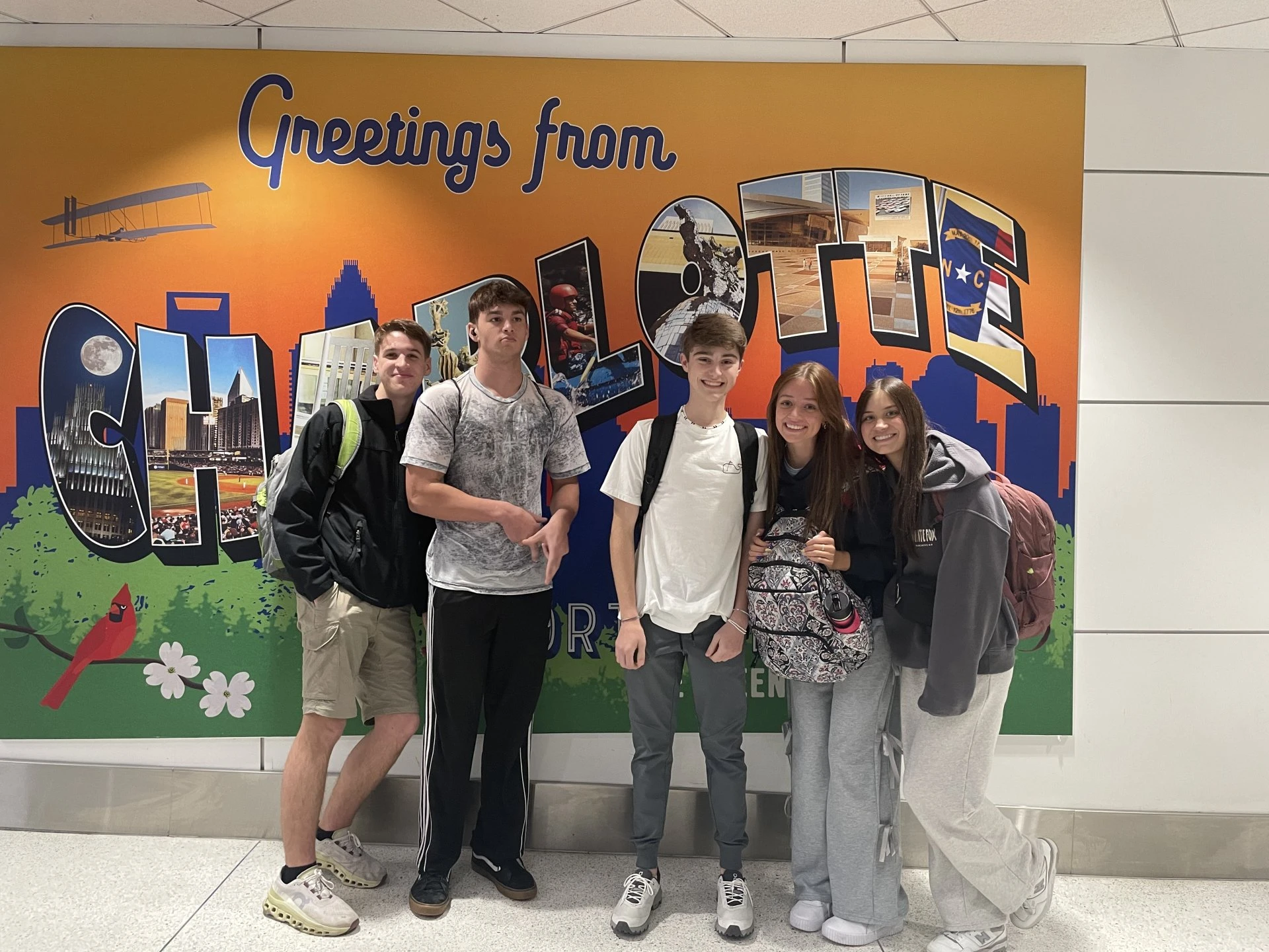 three people standing in front of a wall with a mural