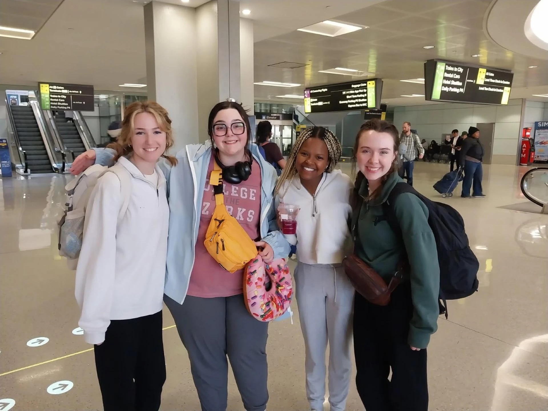 four women are posing for a photo in an airport