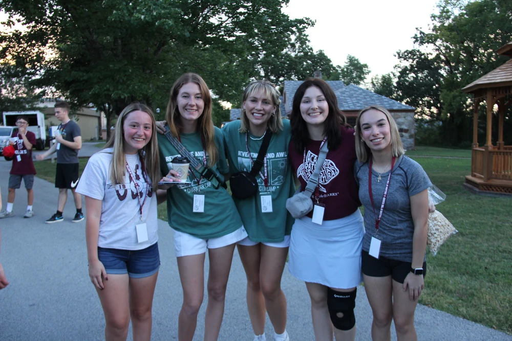 Young women standing together posing for picture.