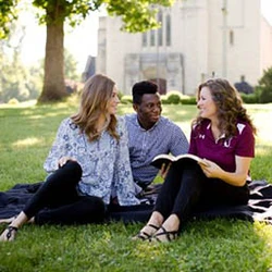 Students setting on lawn in front of chapel