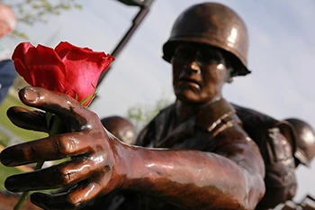 Statue of soldier reaching for flower