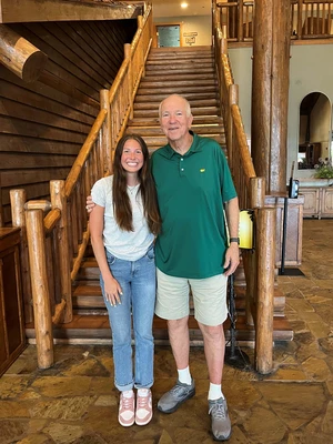 In this picture a tall man is standing next to a girl student in the lobby area of the Keeter Center. 