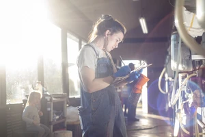 A female student writing data down while working at the dairy farm.