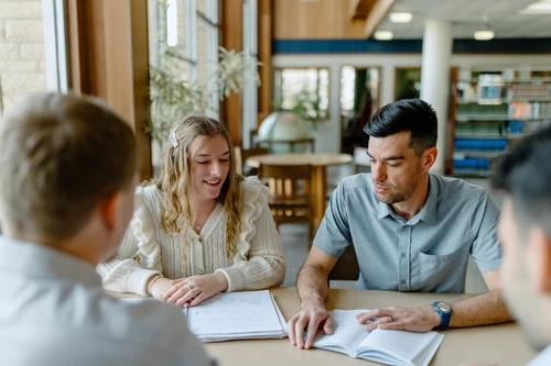 Man sitting with young people at table.