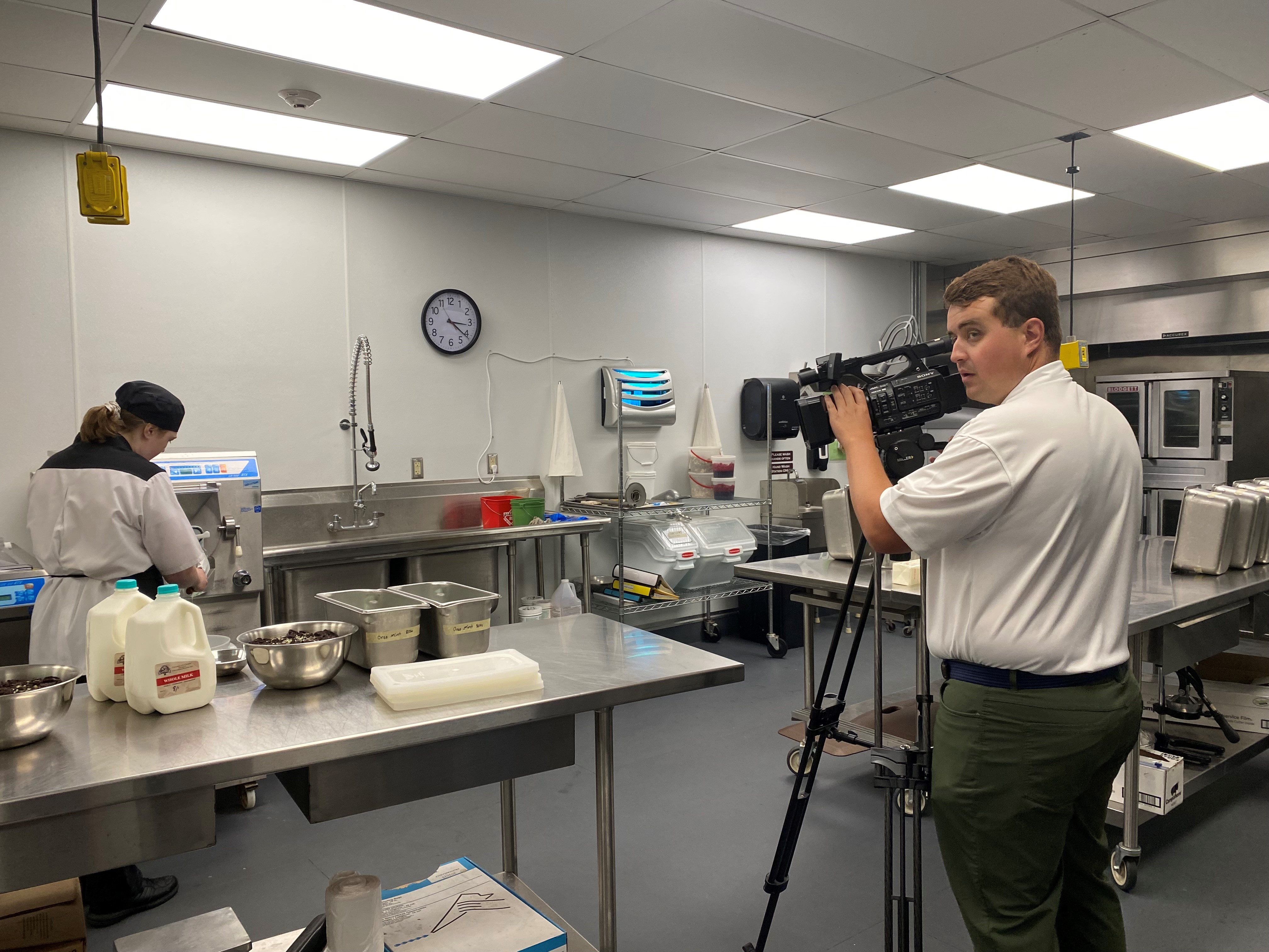Man standing with a large video camera in a industrial kitchen