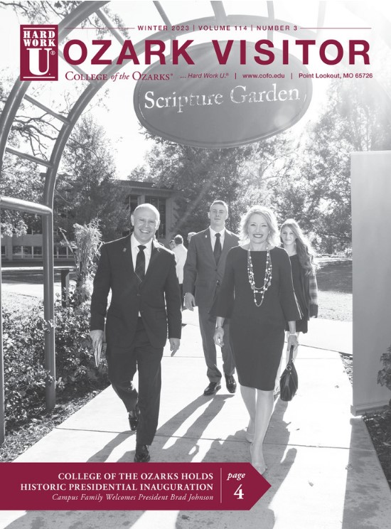 A man and woman walk under an arch with the sign, Scripture Garden