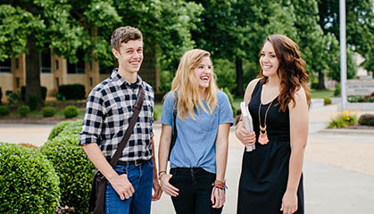 Three students walking across campus.