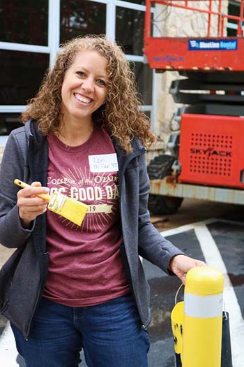 Lori Miller painting a sftey pole at C of O