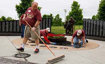 Alumni and veterans cleaning and polishing memorials at Patriots Park