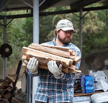 C of O alumnus carries wood to fire up the kilns