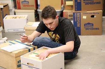 student organizes files as he participates in his family’s service project.