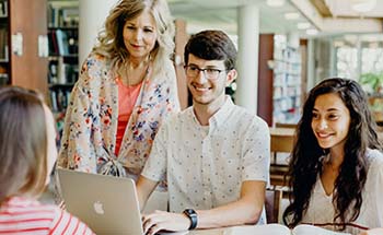 Instructor assists students using laptop