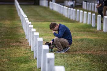 Student kneels by grave in Arlington National Cemetery