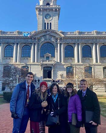 Delegates from C of O stand in front of Mahan Hall at the U.S. Naval Academy in Annapolis, Maryland. (L – R) Senior Gabe Greco; senior Michia Jenkins; Marci Linson, vice president for patriotic activities and dean of admissions; junior Kandice Riley; sophomore Alec Land.