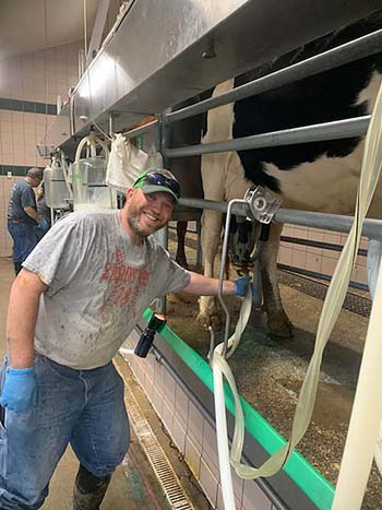 Luke Barnett, hog farm manager, works in the dairy barn, ensuring cows are milked on time. They must be milked at 5 a.m. and 5 p.m., daily.