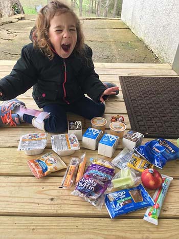 Nancy Webb, a preschooler from Kirbyville School District, is delighted to receive meal items from the school. They provide meals for all their students three times a week. Craig Ernsting, director of food service at the Pearl Rogers Dining Center at College of the Ozarks, gave a donation of surplus food items to the Kirbyville School District.