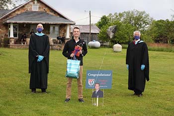 Senior Luke Williams enjoys the surprise visit by bagpipers, school administrators, and a line of vehicles with signs and well wishes.