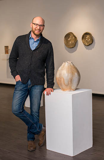 Eric Ordway standing next to a peach-tone tulip-shaped ceramic vase.