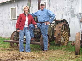 Dr. Howell W. Keeter and his wife in front of a rusty tractor.