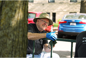 David Davidson of the Alumni Veteran Chapter sands paint off a fence as part of the campus improvements.