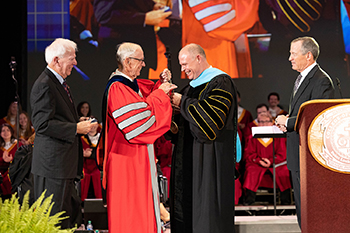 Dr. Jerry C. Davis, chancellor, presents Dr. Brad Johnson with the presidential medallion, along with Shawn McKenzie, chairman of the board of trustees, and General Terrence R. Dake, immediate past chairman of the board of trustees.