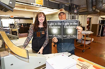 Holly Moore, junior nursing major, shows Rowe the recent flyers coming off the press in the College’s own Print Shop.