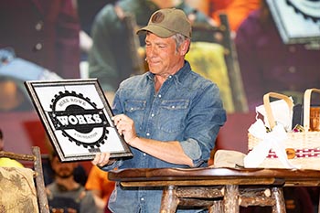 Rowe examines a gift of stained glass representing his foundation. The piece was handmade by the students in the Stained Glass & Candle Shop on campus.